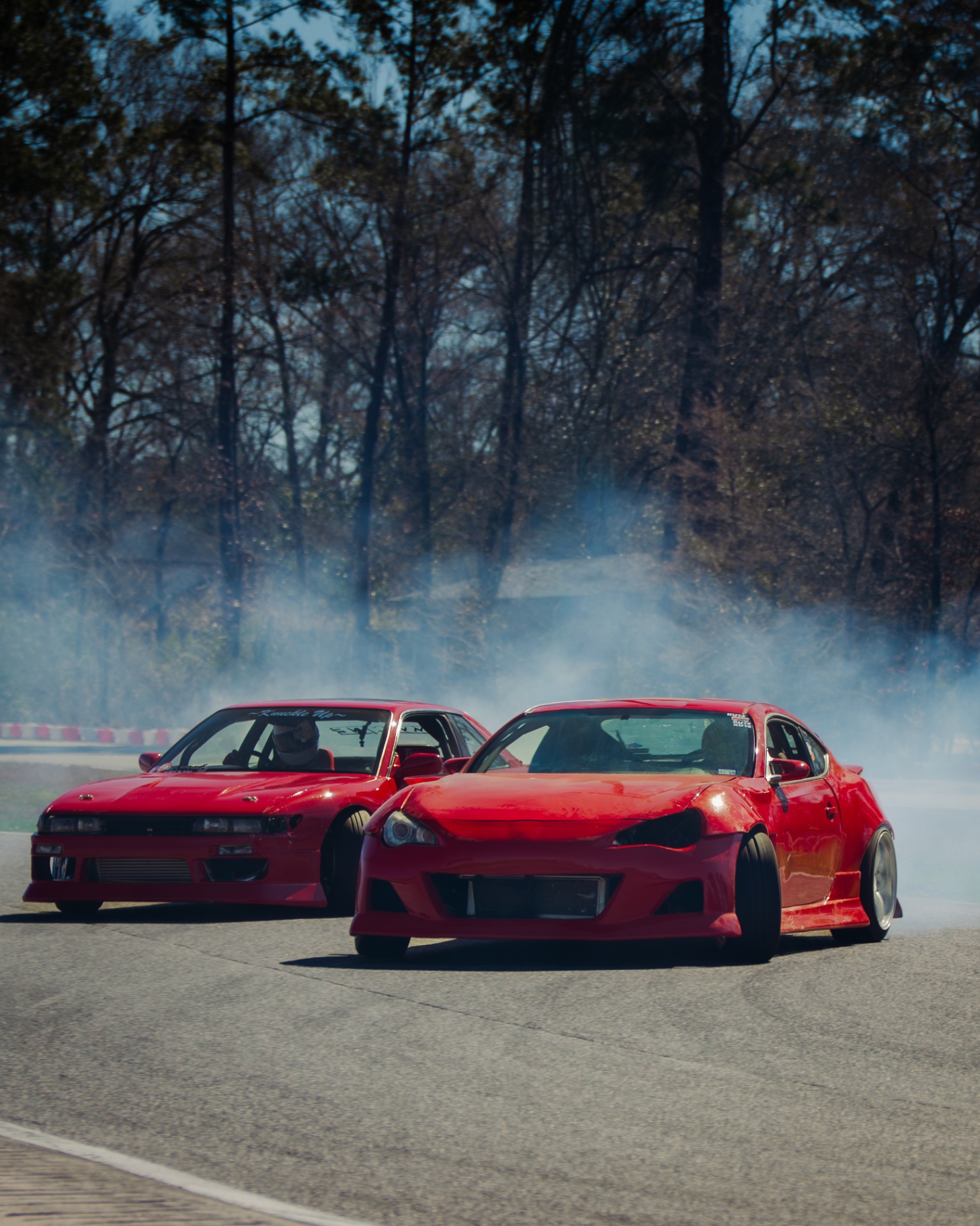 Tandem red drift cars trailing smoke